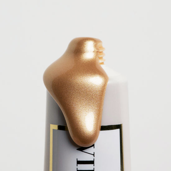 Close up image of VIEVE's iconic Skin Dew with product overflowing highlighting the glow of the liquid highlighter