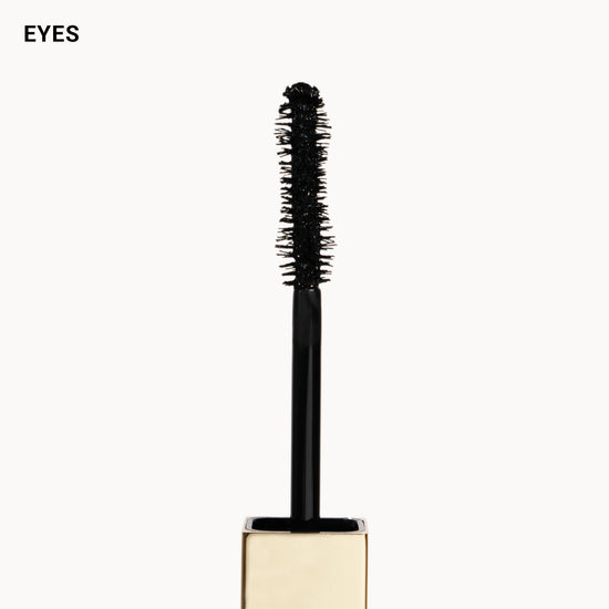 Mascara wand with gold base on a white background, labeled 'EYES'.