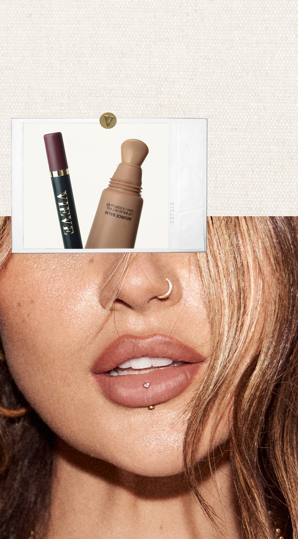 Close-up of Jamie Genevieve's lower face with nose and lip piercings, layered with a Polaroid-style photo of two Vieve beauty products — a Modern Lip Definer and a Bounce Balm lip balm.